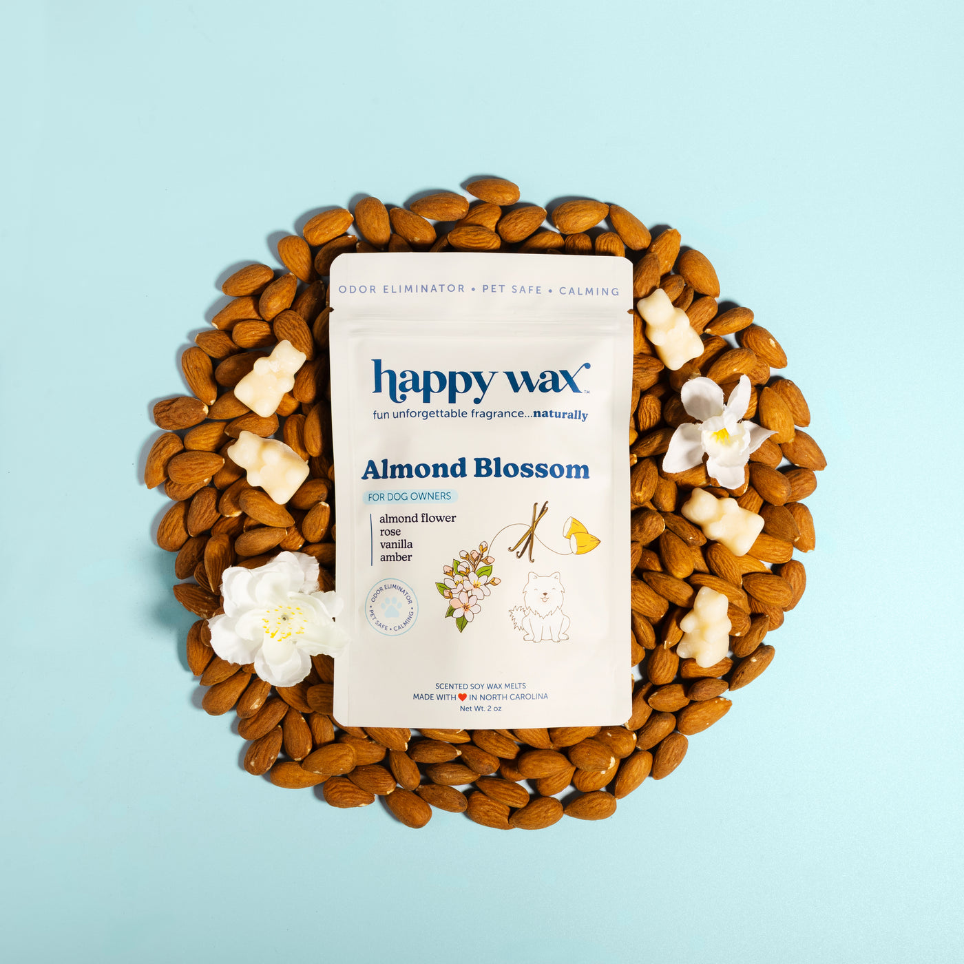 Happy Wax Almond Blossom pet-safe wax melts package surrounded by almonds and white flowers on light blue background.