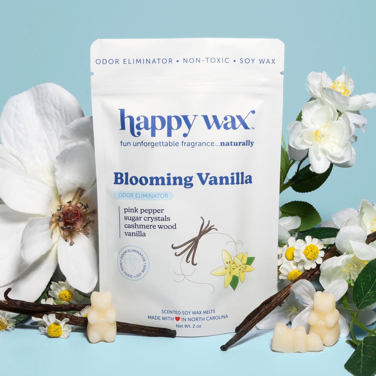 White wax melts in bear shapes displayed with vanilla pods and white flowers on blue background.