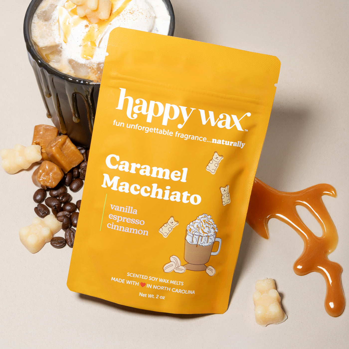 Yellow Happy Wax pouch of Caramel Macchiato wax melts with cream and brown wax pieces and coffee beans nearby.