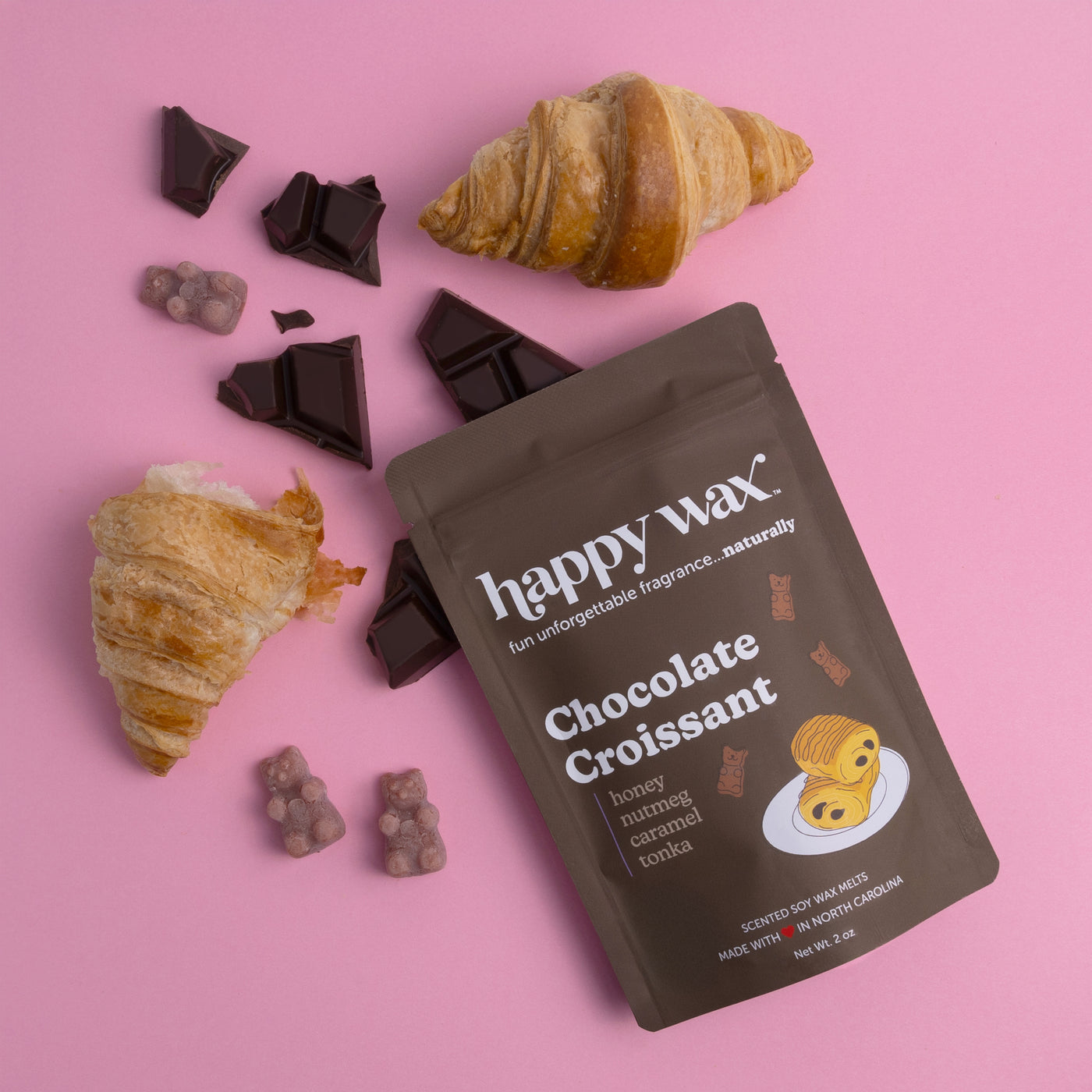 Chocolate Croissant wax melts package with dark chocolate pieces, croissants, and small wax melts on pink background.
