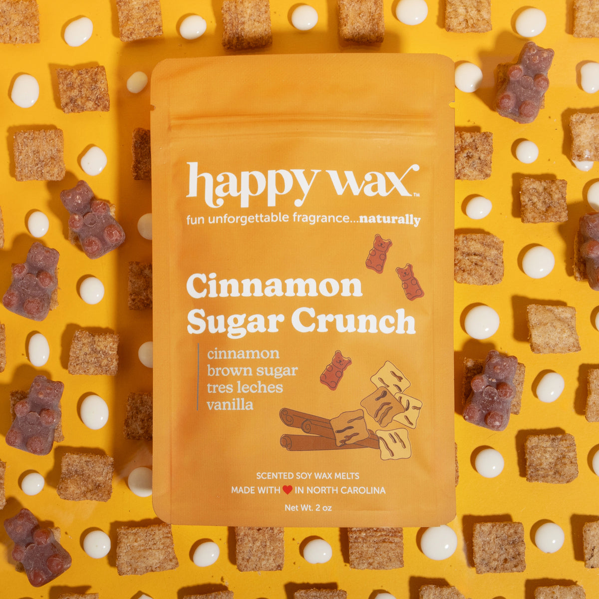 Orange pouch of Happy Wax cinnamon sugar crunch scented soy wax melts surrounded by brown sugar cube pieces and white dots on