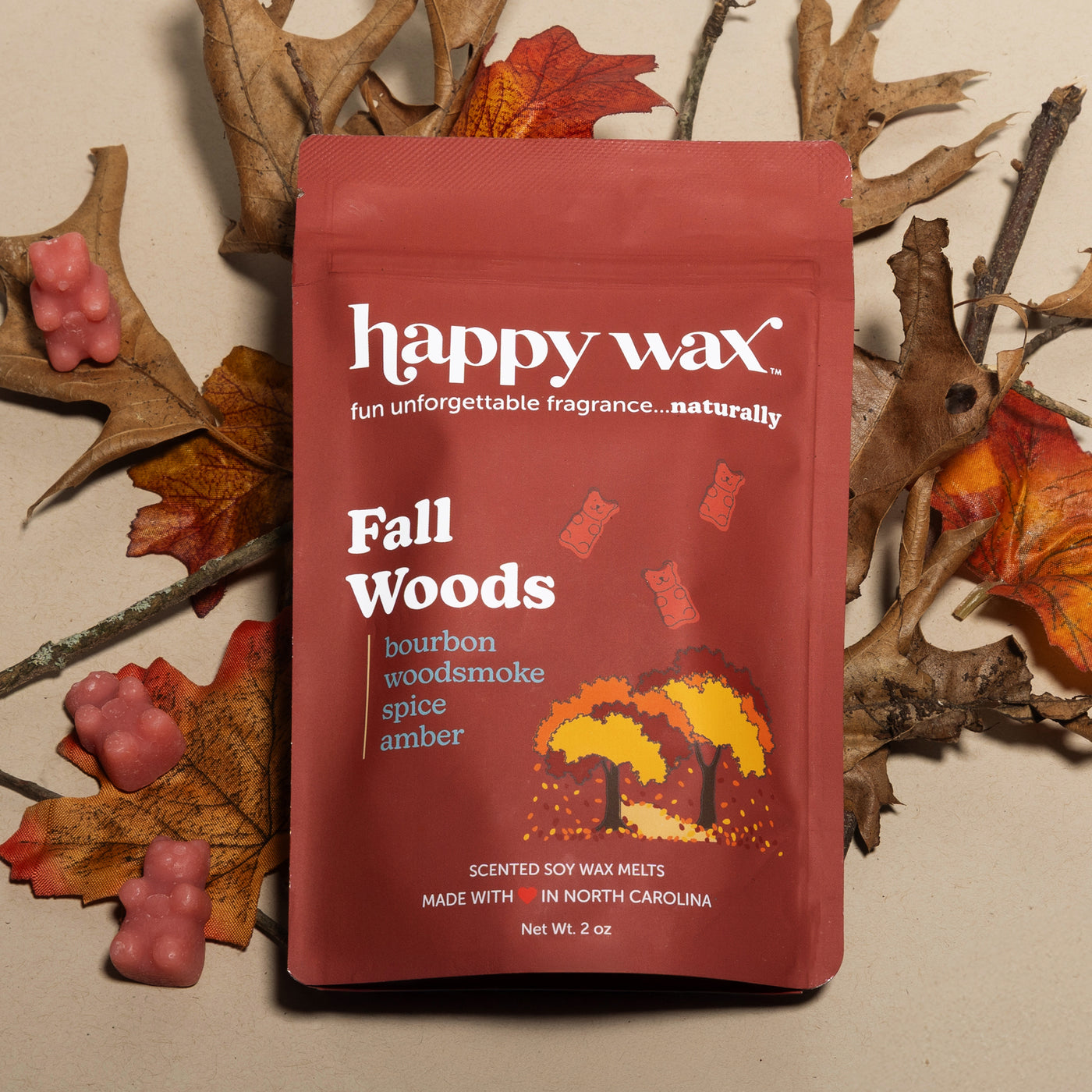 Red Happy Wax Fall Woods wax melt package surrounded by dried branches and autumn leaves.