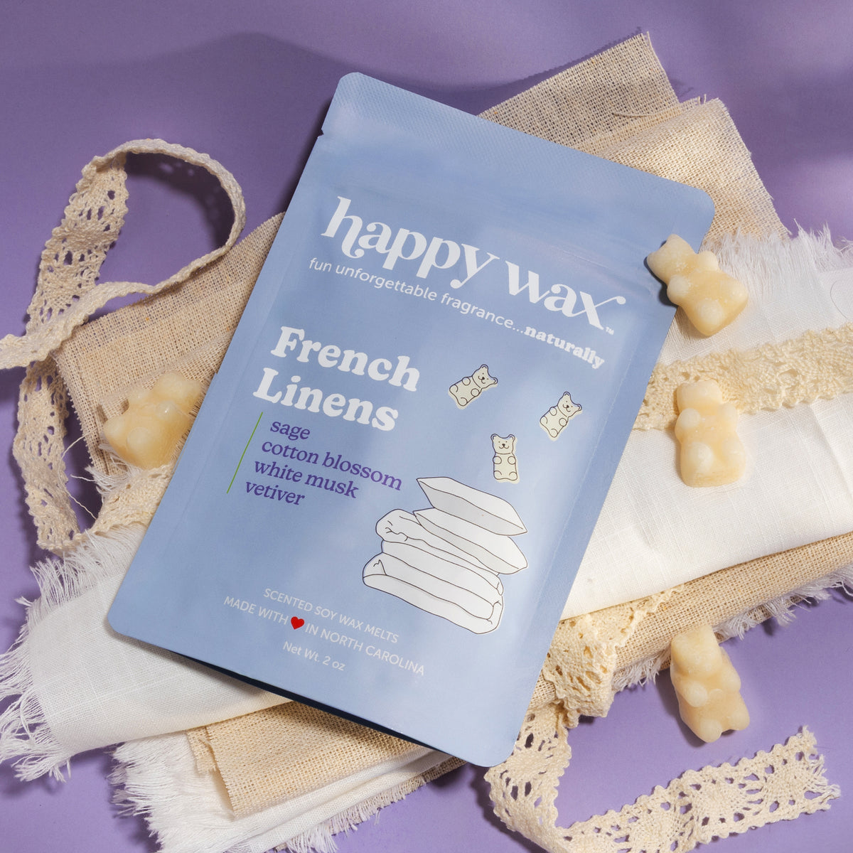 Happy Wax French Linens packaging with linen fabric and ribbon on purple background