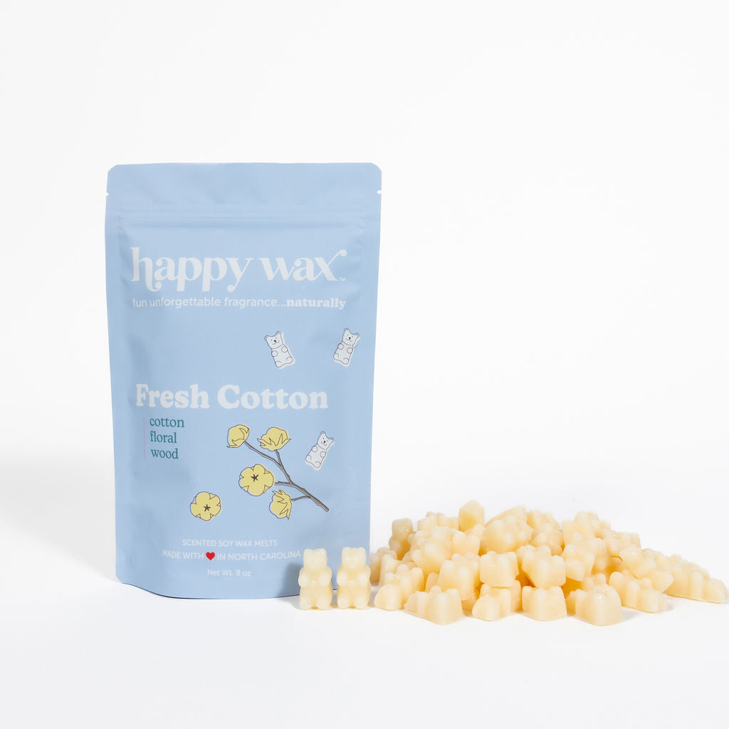 Light blue pouch of Happy Wax Fresh Cotton wax melts with cream-colored wax cubes scattered beside it.