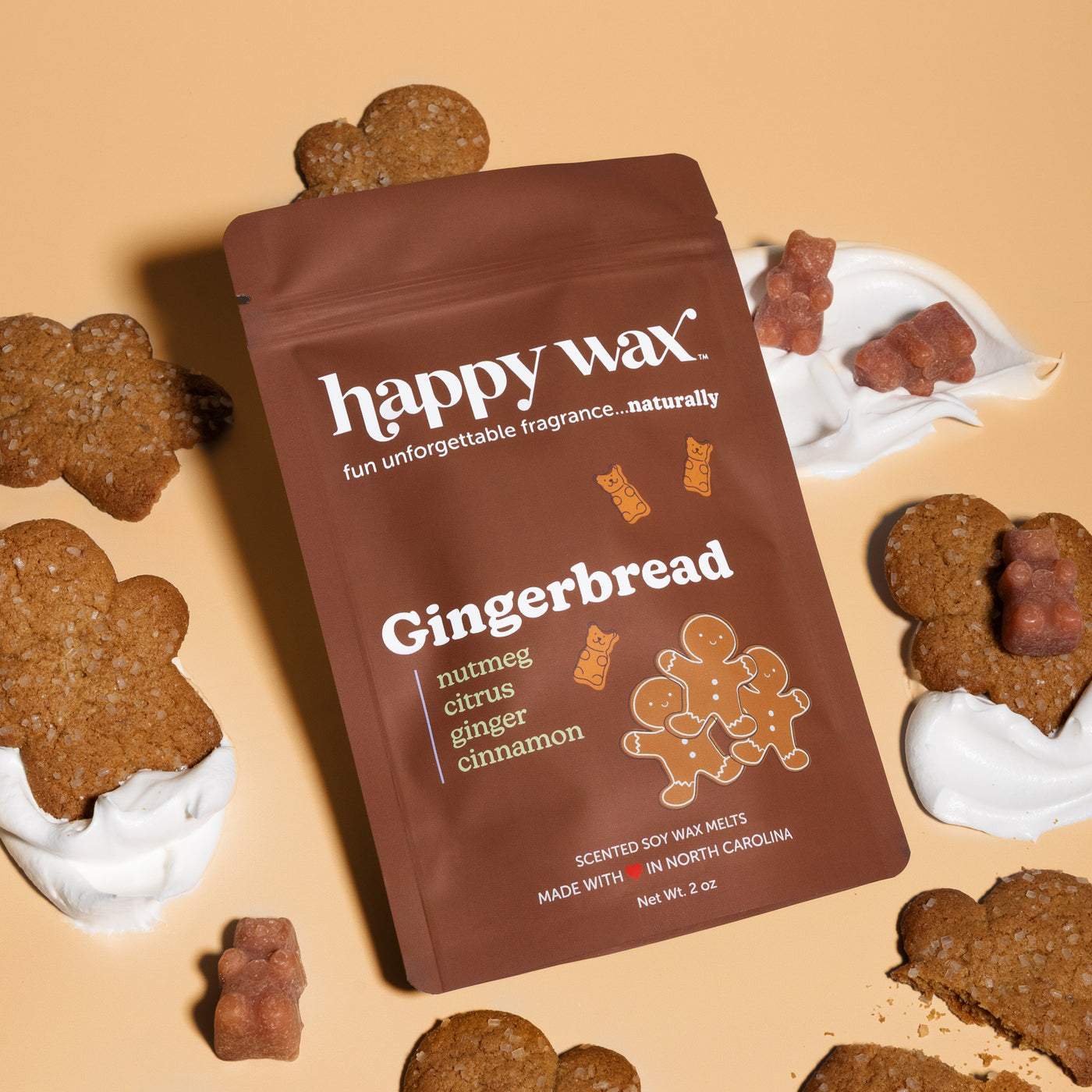 Brown Happy Wax pouch of Gingerbread wax melts surrounded by gingerbread cookies and melts in white dishes on tan background.