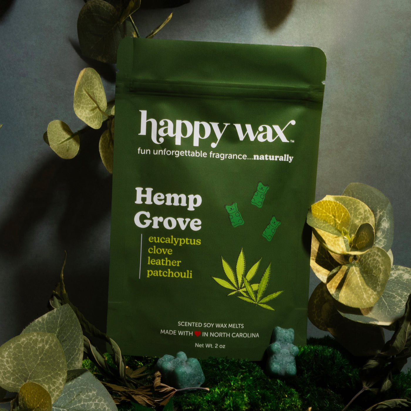 Green pouch of Hemp Grove soy wax melts surrounded by dried eucalyptus leaves and moss.