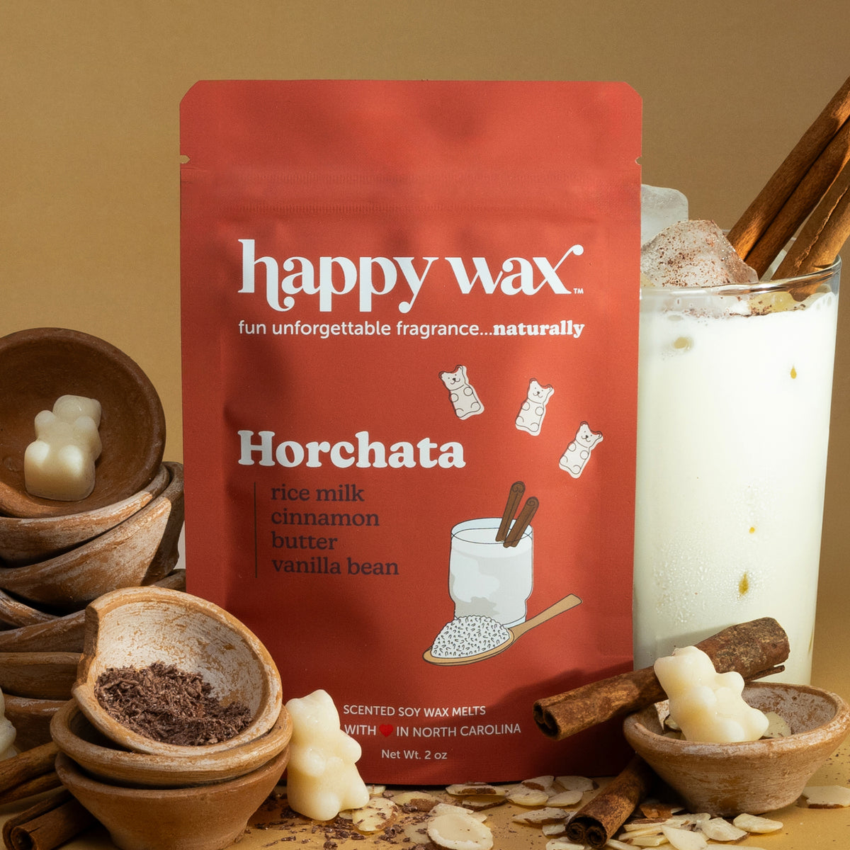 Red Happy Wax pouch of Horchata scented soy wax melts surrounded by cinnamon sticks, wooden bowls, and cream-colored wax piec