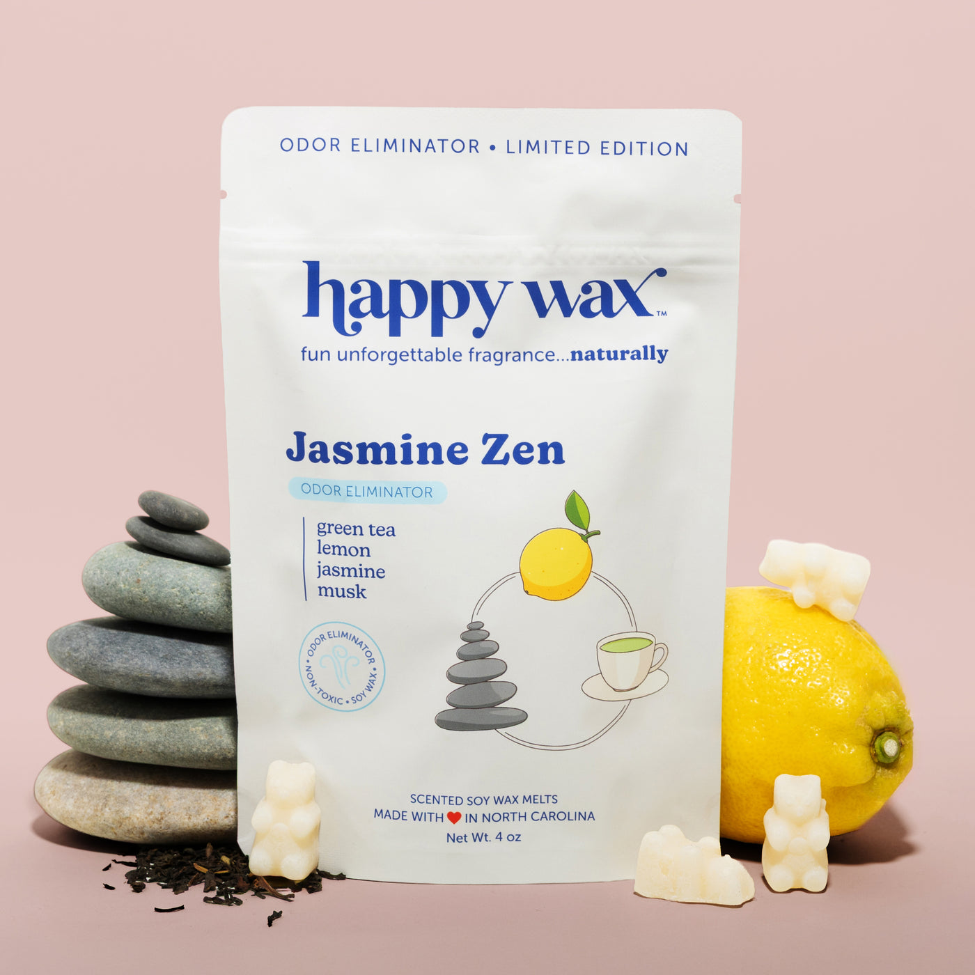 Happy Wax Jasmine Zen pouch with lemon, tea leaves, and stacked smooth rocks on pink background