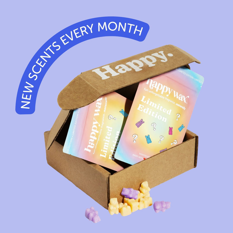 Cardboard subscription box containing colorful "Happy Wax" product boxes and scattered wax melts against a lavender backgroun