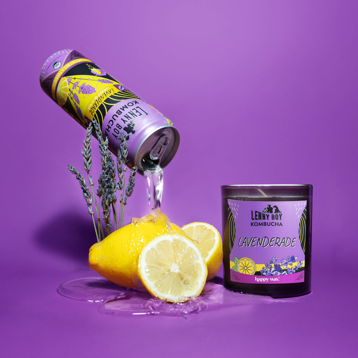 Purple single wick candle with yellow and purple label beside fresh lemons and dried lavender sprigs against purple backgroun