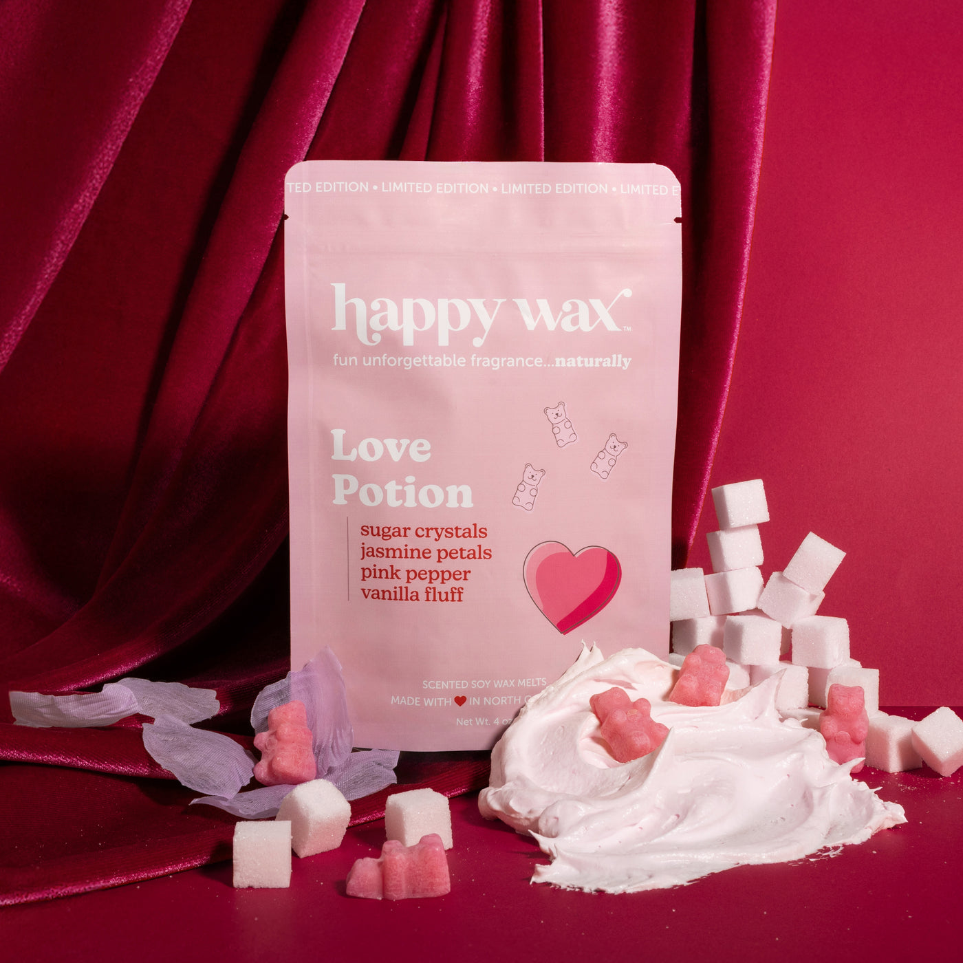 Pink pouch of Love Potion wax melts surrounded by white and pink wax cubes on burgundy fabric background.