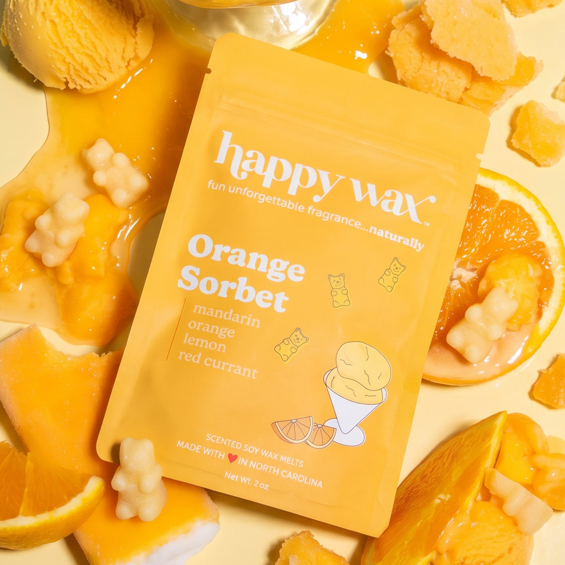 Yellow pouch of Orange Sorbet wax melts surrounded by orange slices, wax melts, and ice cream styling.