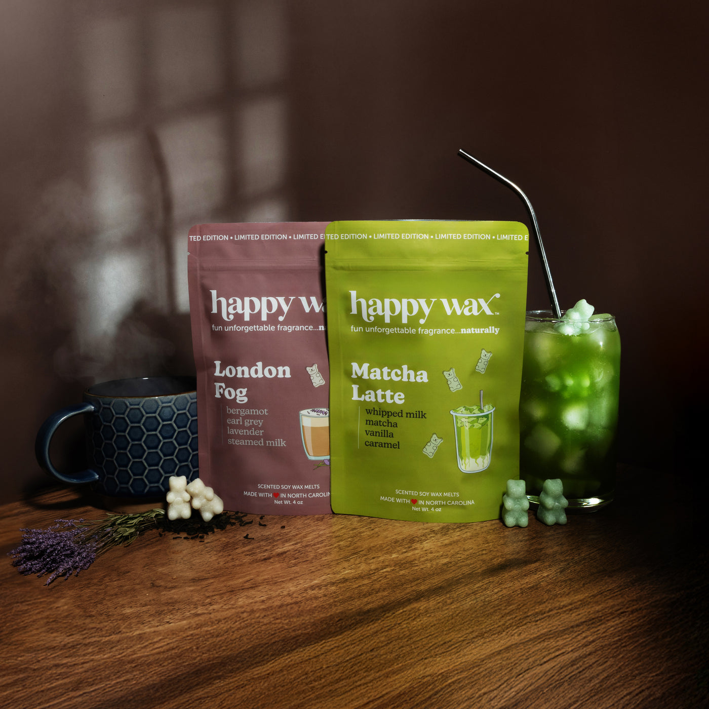 Two scented soy wax melt packets—London Fog and Matcha Latte—displayed with a mug, glass, and decorative elements on wood sur