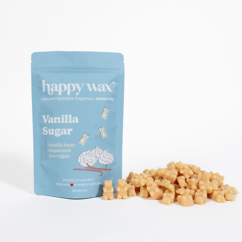 Blue pouch of Happy Wax vanilla sugar wax melts with cream-colored cube-shaped melts scattered beside it.