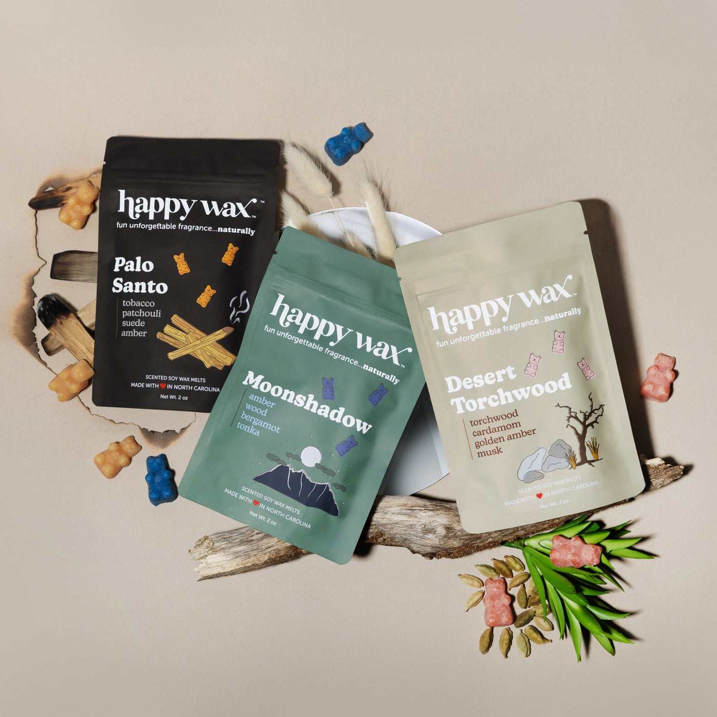 Three happy wax scented sachets in Palo Santo, Moonshadow, and Desert Torchwood arranged with decorative branches and dried b