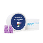 Purple bear-shaped wax melts next to a white container labeled "Blue Iris & Cognac" with navy lid and a white jar with blue t