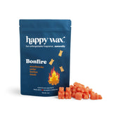 Dark blue Happy Wax pouch with Bonfire scent label and scattered orange wax melt cubes beside it.
