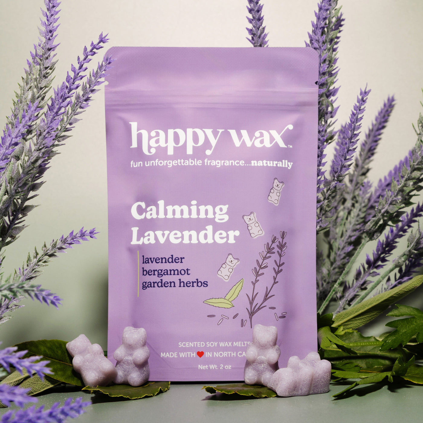Purple pouch of lavender wax melts surrounded by dried lavender sprigs and small wax melt pieces.
