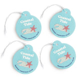Four turquoise round car charms with white string, each featuring "Coastal Tide" text, a starfish, shell illustration, and sc