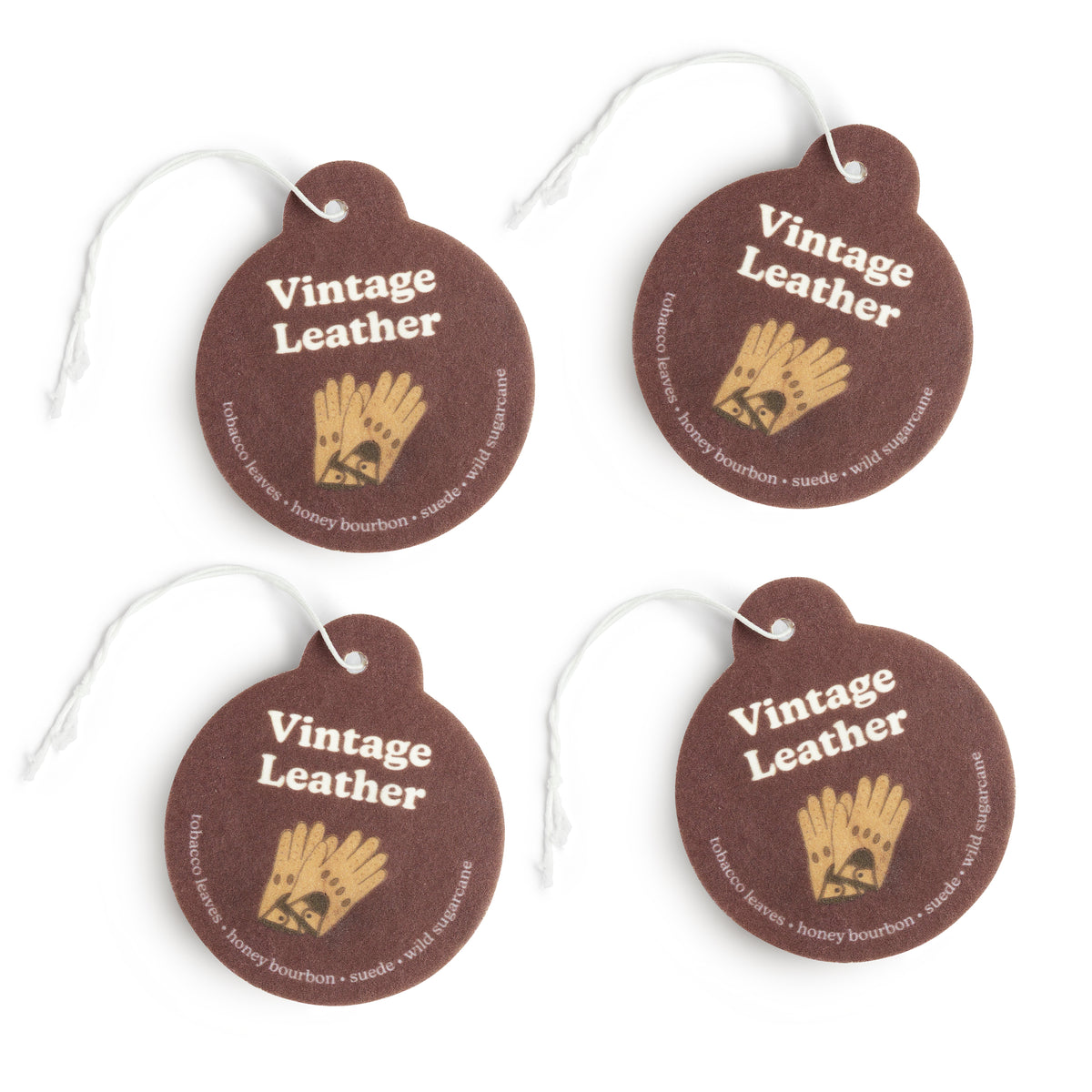 Four brown leather round charms with gold wheat design, white text, and white string attachments.