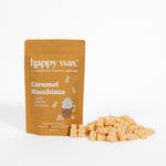 Gold pouch of Happy Wax Caramel Macchiato wax melts with scattered tan wax pieces beside it.