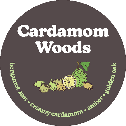Dark gray circular label with white "Cardamom Woods" text and illustrated cardamom pods, lemon slices, and leaves, with green