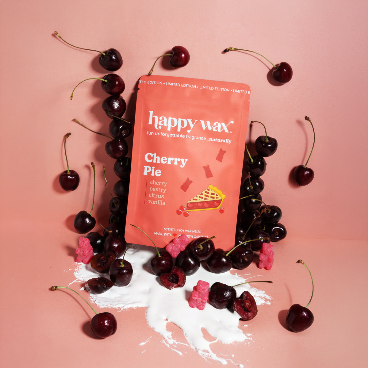 happy wax Cherry Pie wax melt packaging surrounded by cherries and cream on a pink background