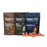 Three pouch-style wax sachets in brown, black, and navy with scattered orange wax melts in front.