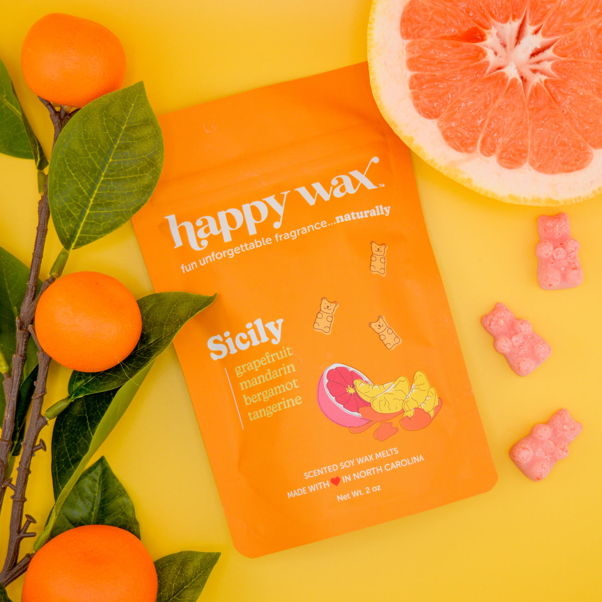 Orange "happy wax" Sicily scented wax melt package with grapefruit halves and small pink wax cubes on yellow background.