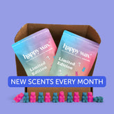 Brown cardboard box containing two gradient-colored Happy Wax Limited Edition candle packages with pink and blue wax melts ar