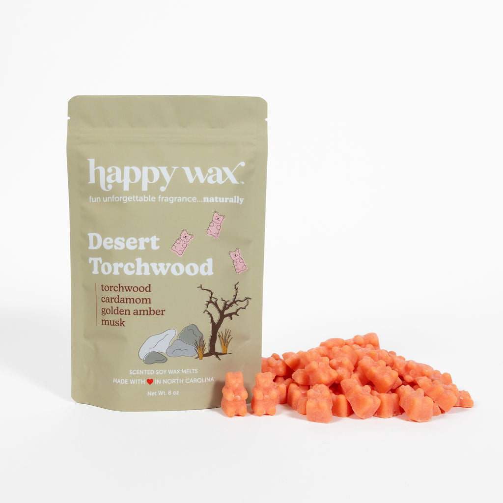 Tan pouch of Happy Wax Desert Torchwood wax melts with orange cube-shaped melts scattered beside it.