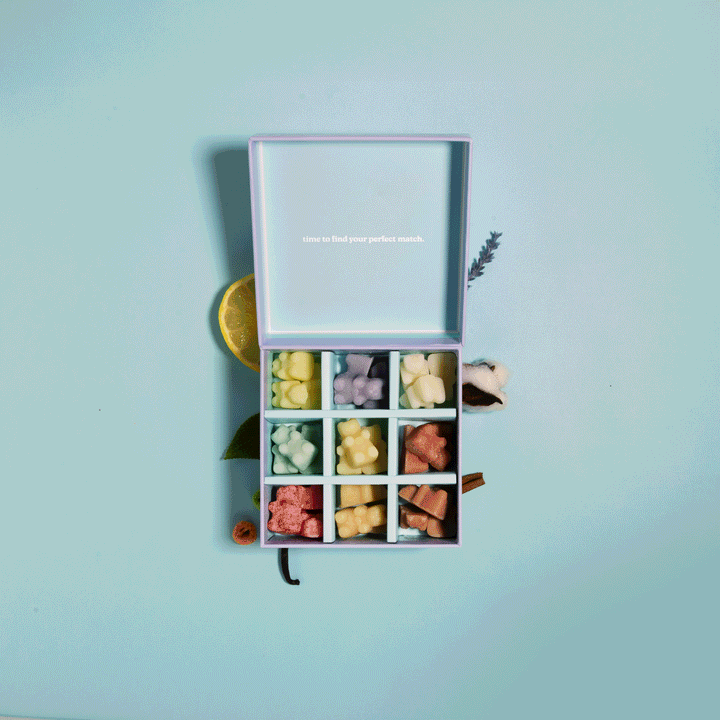 Wax melt discovery kit with nine compartments containing assorted colored wax melts in yellow, pink, and coral tones.