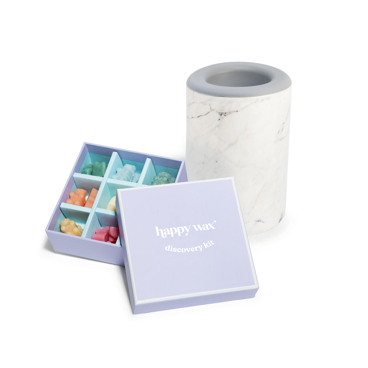 Wax melt discovery kit with assorted colored wax chunks in purple box and marble-textured warmer with gray rim.