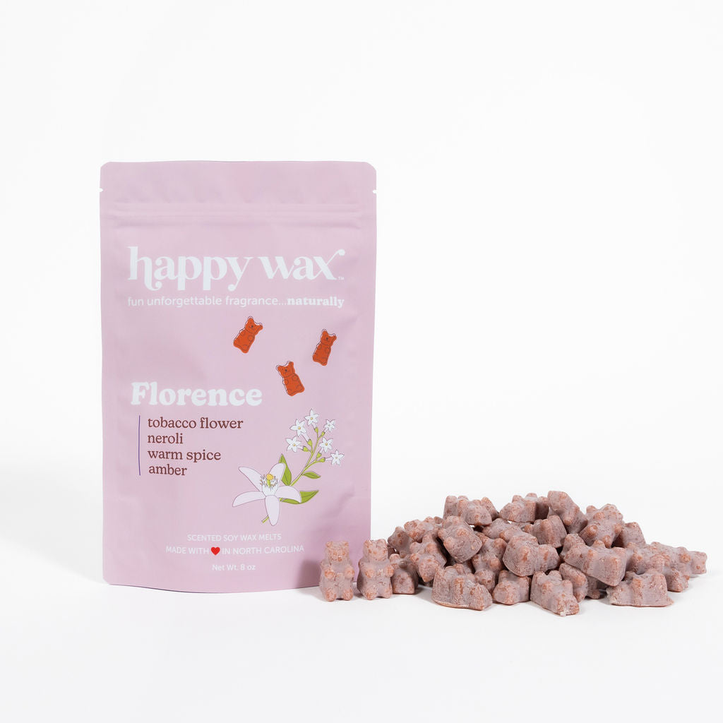 Pink pouch of Florence wax melts next to scattered brown wax cubes on white background.