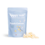 Light blue pouch of Happy Wax Fresh Cotton scented soy wax melts with cream-colored wax pieces displayed in front.