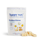 Cream-colored wax melts scattered beside Happy Wax Golden Citrus pouch featuring citrus illustrations and cat and dog graphic