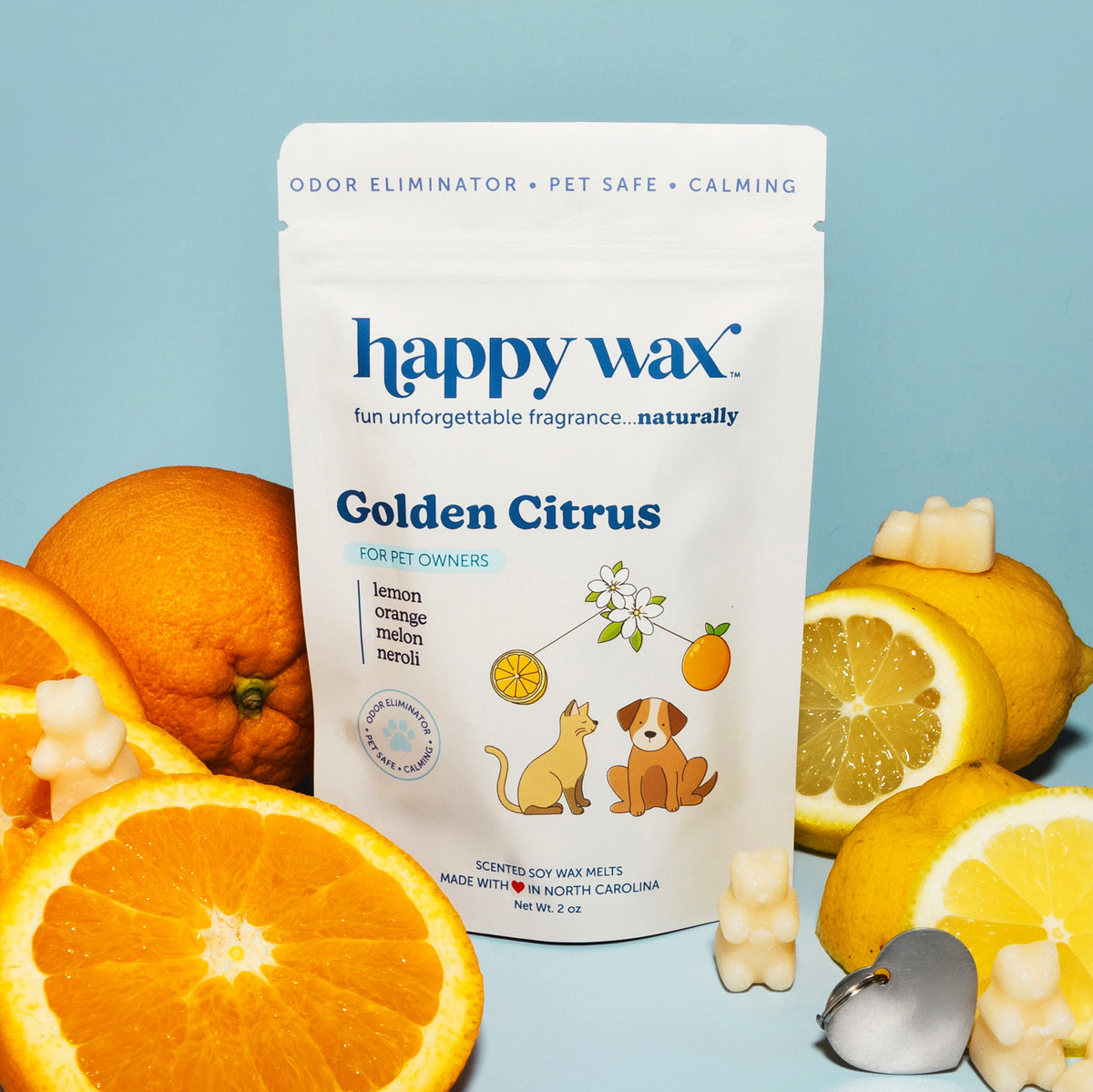Happy Wax Golden Citrus pet-safe wax melts pouch surrounded by citrus fruit slices and wax melt pieces on blue background.