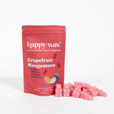Red pouch of Happy Wax grapefruit mangosteen wax melts with pink wax cubes scattered beside it.