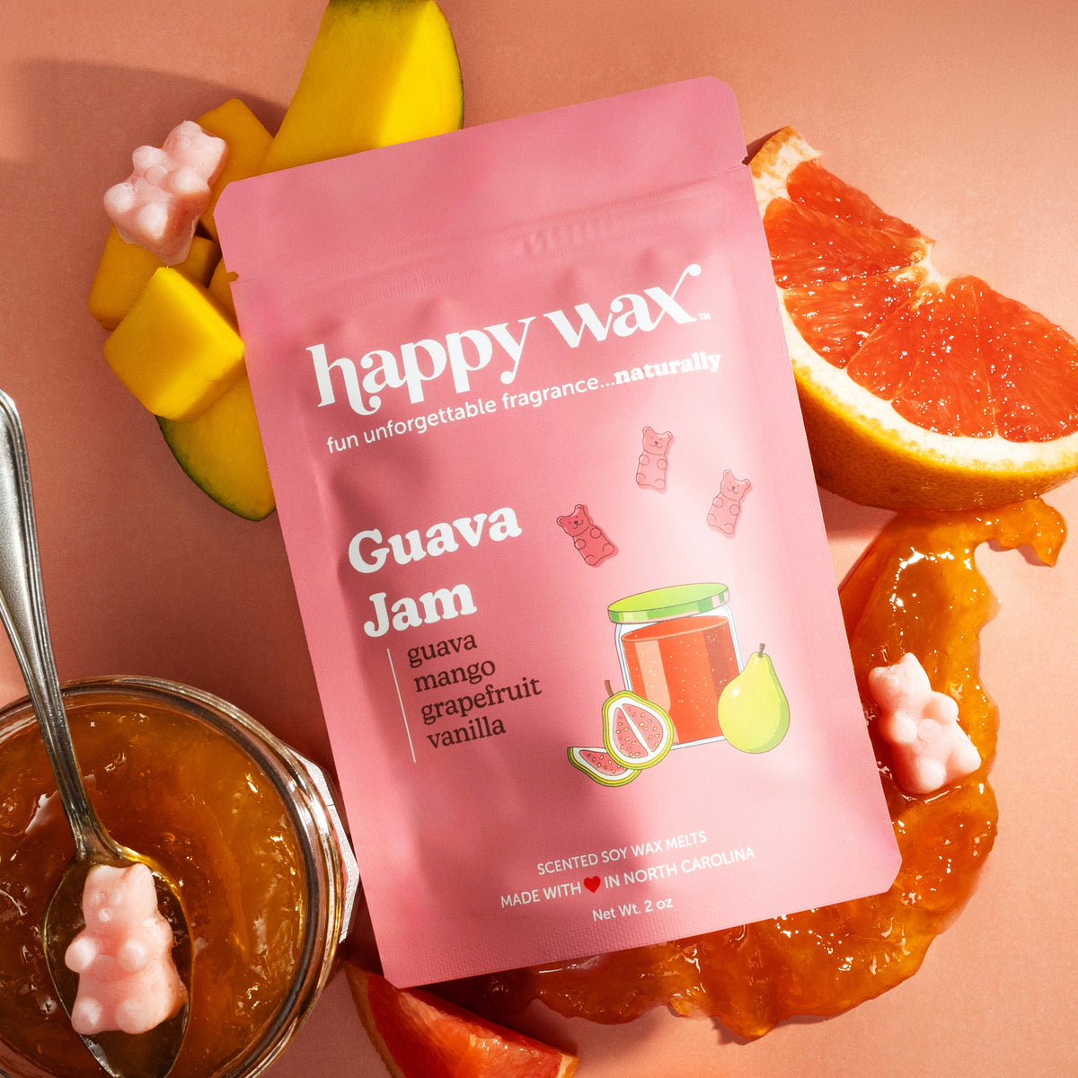 Pink pouch of Happy Wax guava jam scented soy wax melts surrounded by grapefruit slices, guavas, and pink wax melts.
