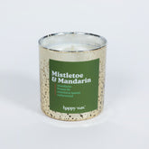 Cream-colored speckled candle jar with green label reading "Mistletoe & Mandarin" and single lit wick inside.