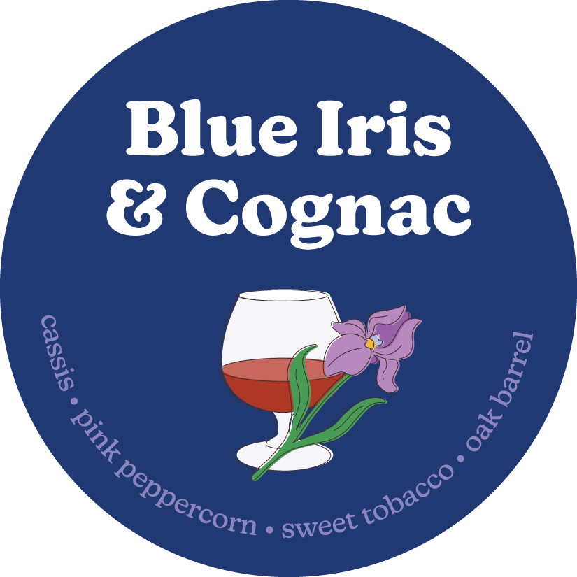Round navy label featuring white text, an illustration of a cognac glass with a purple iris flower, and scent notes including