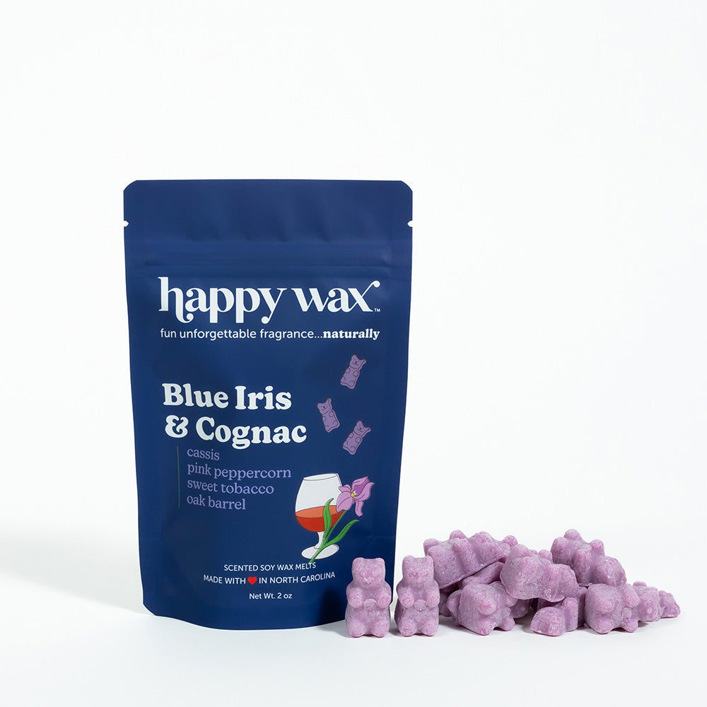 Navy blue pouch of Happy Wax brand Blue Iris & Cognac wax melts with purple wax pieces displayed in front.