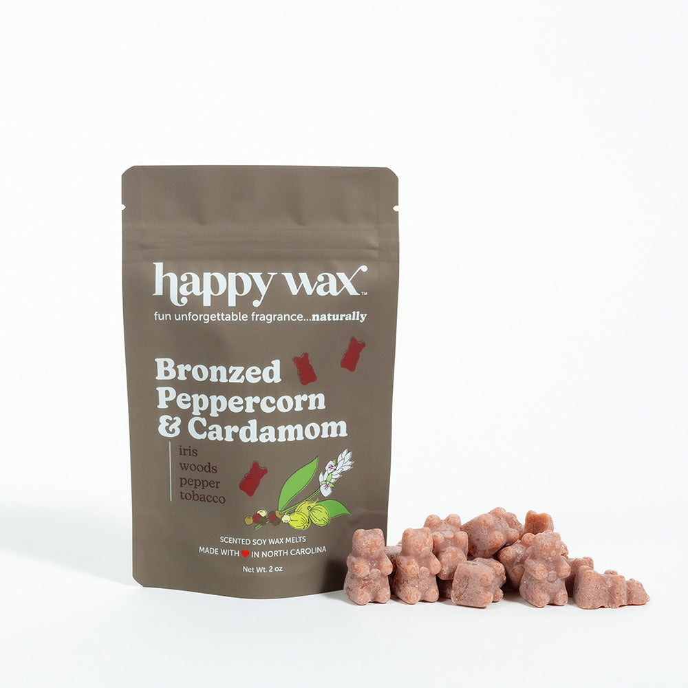 Brown pouch of Happy Wax soy wax melts in Bronzed Peppercorn & Cardamom scent with individual wax cubes displayed beside it.