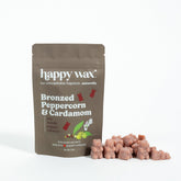 Brown pouch of Happy Wax soy wax melts in Bronzed Peppercorn & Cardamom scent with individual wax cubes displayed beside it.