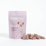 Pink pouch of Happy Wax Florence wax melts with scattered tan-colored wax pieces beside it.