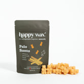 Olive-green pouch of Happy Wax Palo Santo wax melts with beige wax pieces displayed in front.