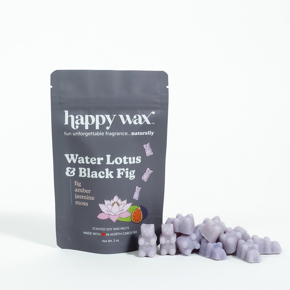 Gray pouch of Happy Wax brand Water Lotus & Black Fig scented soy wax melts with purple wax pieces displayed beside it.