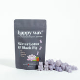 Gray pouch of Happy Wax brand Water Lotus & Black Fig scented soy wax melts with purple wax pieces displayed beside it.