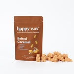 Tan wax melts scattered next to brown Happy Wax pouch labeled "Salted Caramel" with caramel candy illustrations.