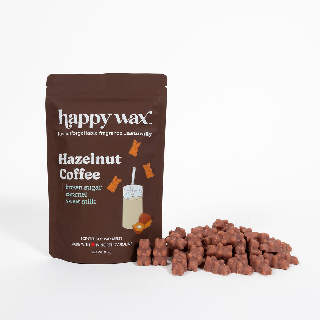 Brown pouch of Happy Wax hazelnut coffee scented soy wax melts with scattered terracotta-colored wax chunks displayed in fron